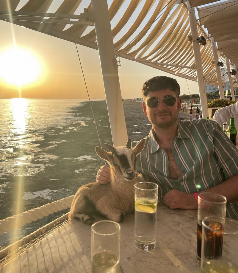 Cavner Bridge at a sunset beach bar with a goat beside him