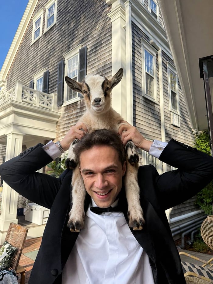 Mark Brewer in a tuxedo with a goat perched on his shoulders