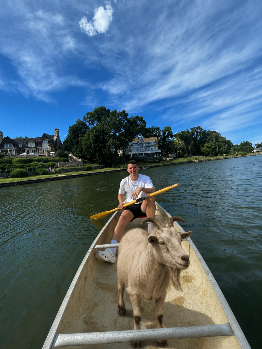 Moe Manson paddling a canoe with a goat standing at the bow