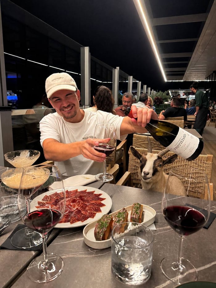 Sam Gautry enjoying dinner with a goat seated beside him